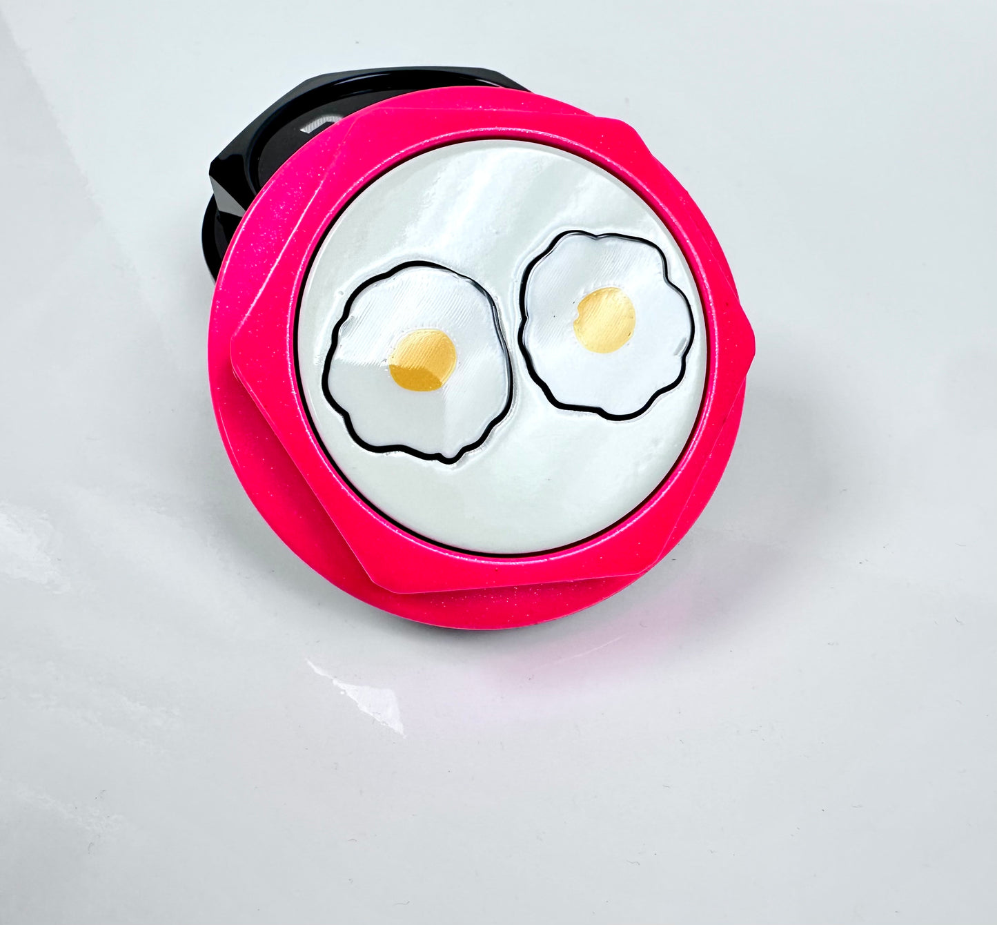 Pink center cap with cartoon-style fried eggs on a white background