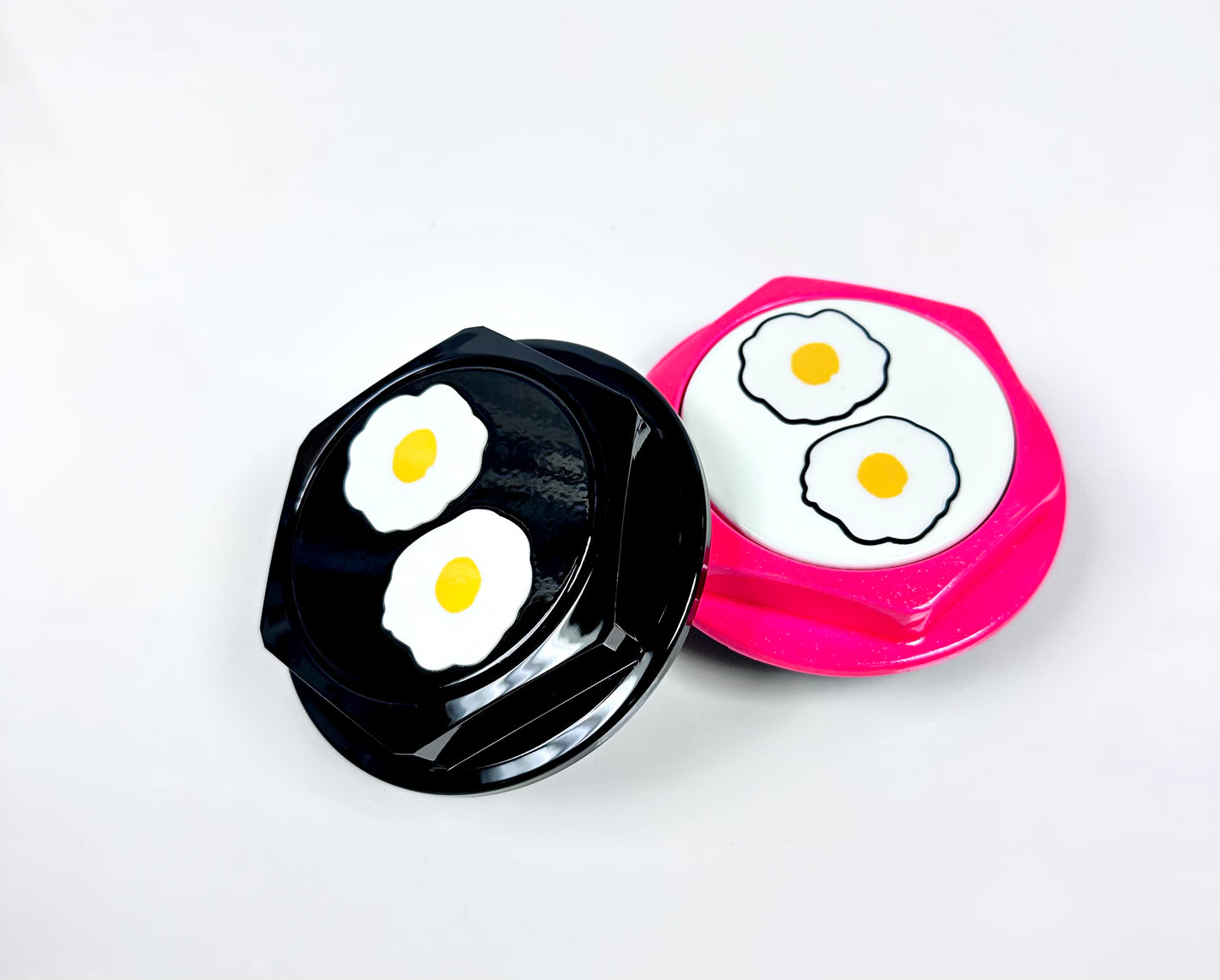 Two hex shaped center caps with egg illustrations on a white background