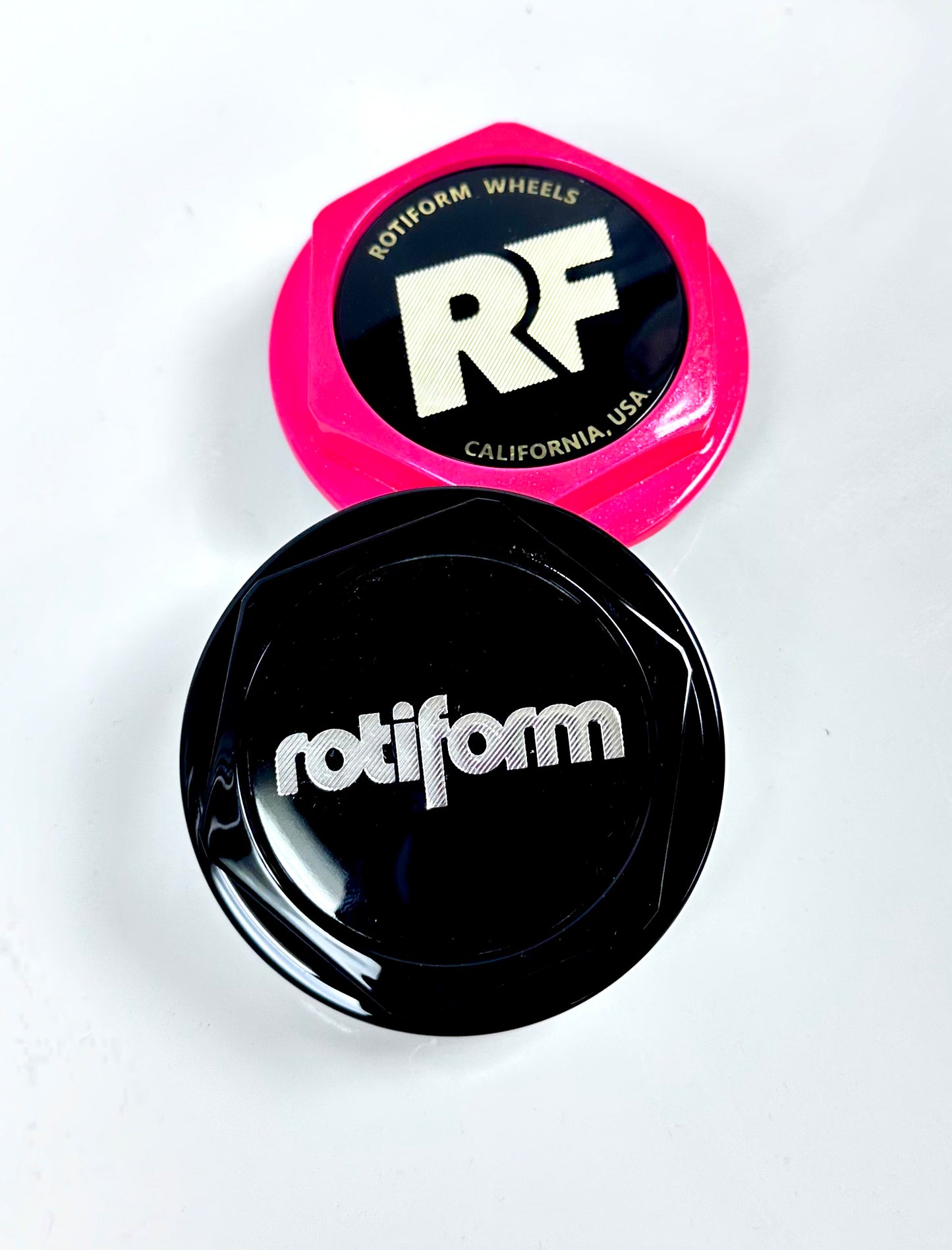 Two car wheel rim caps, one pink and one black, with 'Rotiform' branding on a white background.