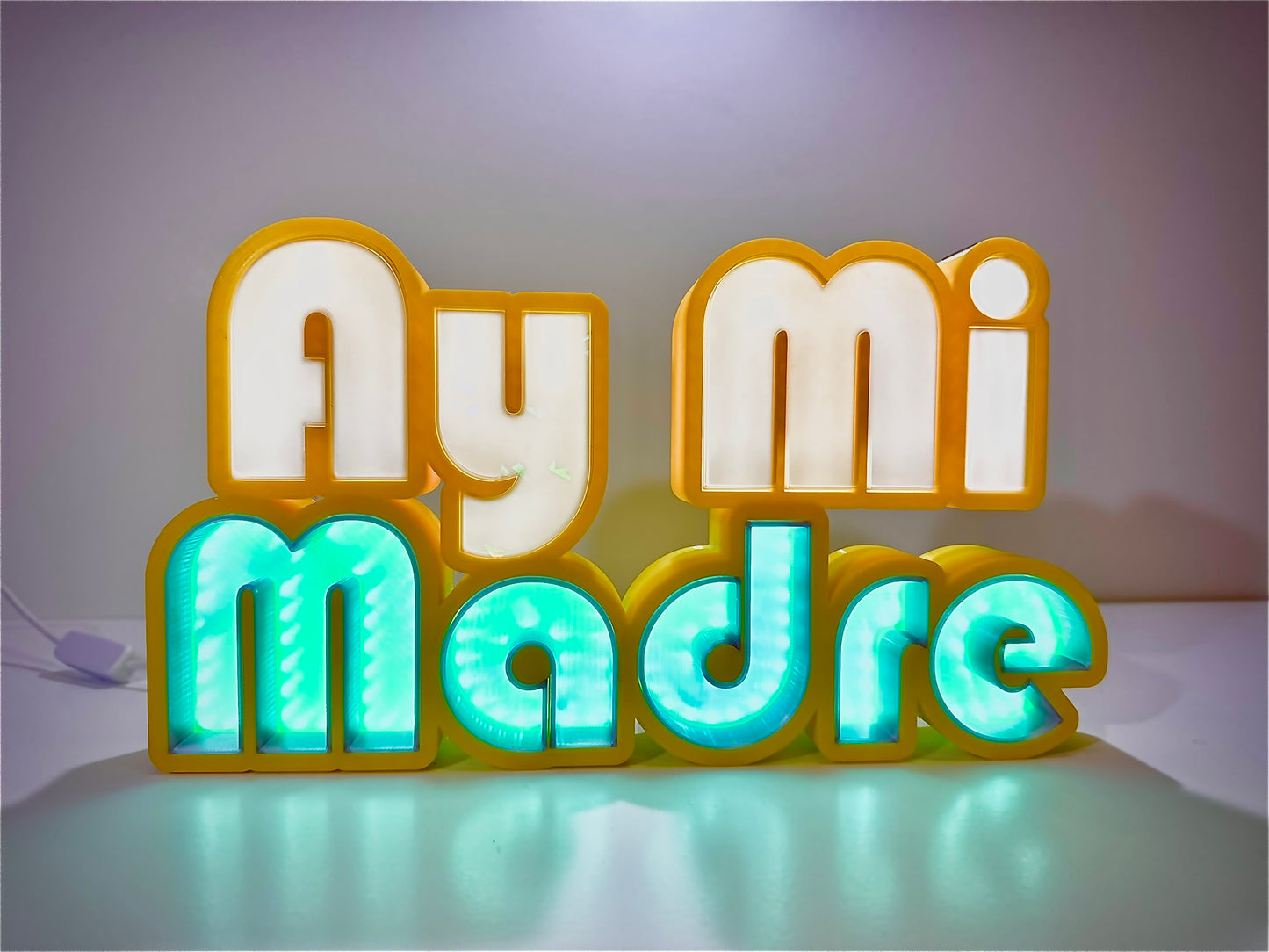 Ay Mi Madre LED Channel Letter Sign illuminated in yellow with green letters, displayed against a white background