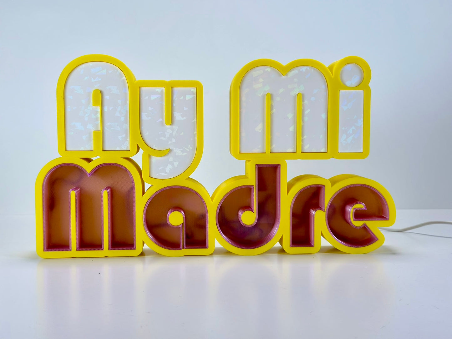 Front view of Ay Mi Madre LED Channel Letter Sign in yellow with white letters, illuminated with a green light against a white background.