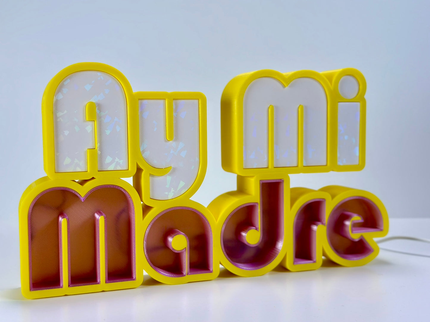 Angled side view of Ay Mi Madre LED Channel Letter Sign in yellow with white letters, illuminated with a green light against a white background.
