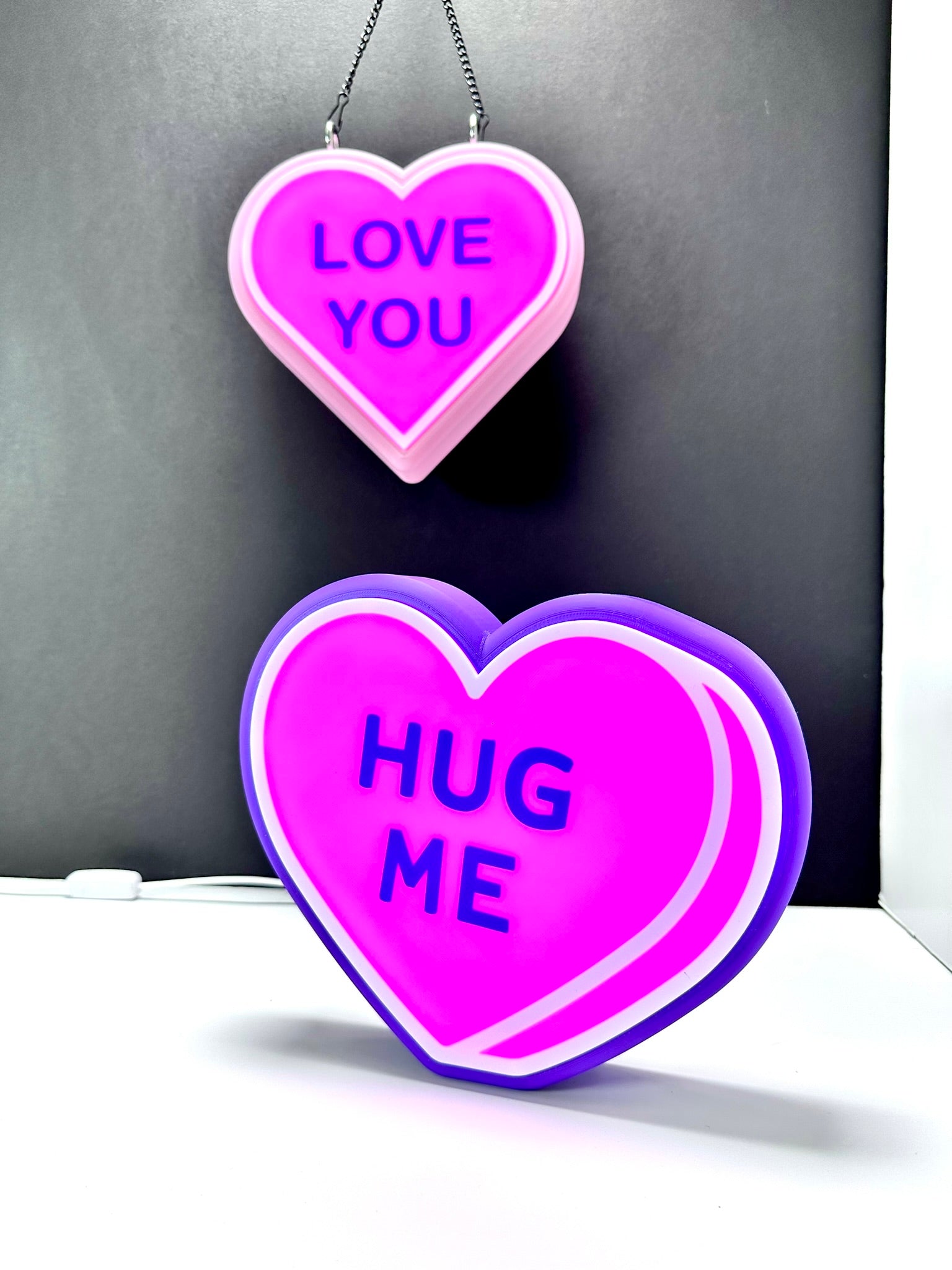 Glowing LED heart signs: pink 'LOVE YOU' and purple 'HUG ME.' Custom Valentine décor.