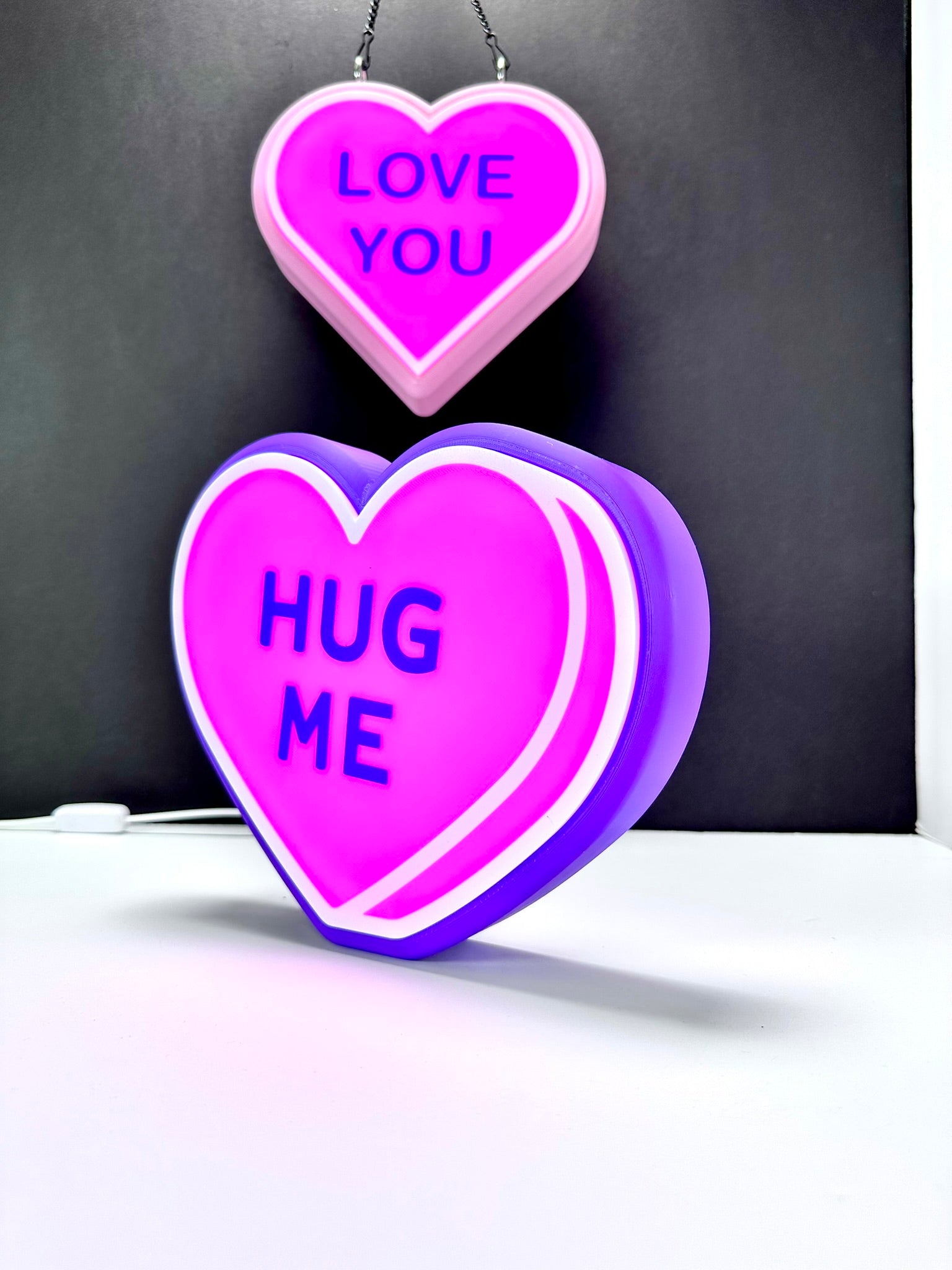 Pair of LED heart signs: pink 'LOVE YOU' and purple 'HUG ME.' Valentine’s décor.