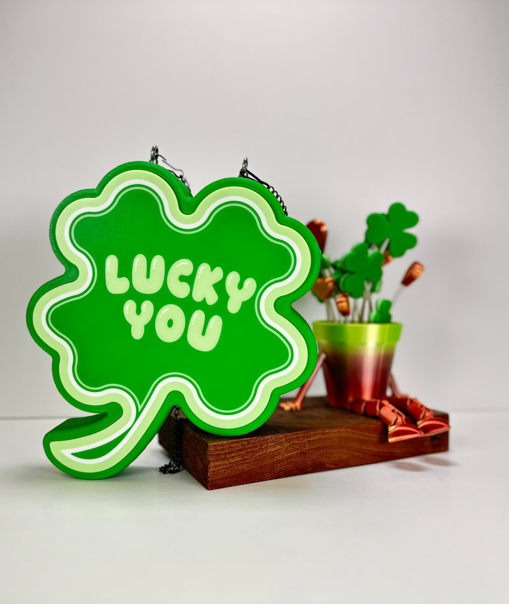 Custom 3D-printed Shamrock LED sign placed on a wooden stand, paired with festive green and copper decorations