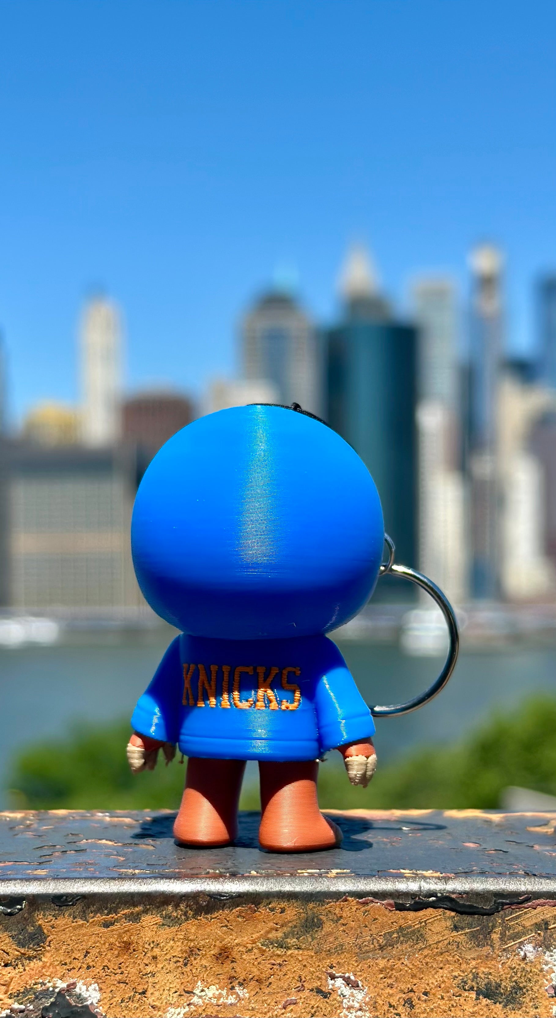 Blue figurine with 'Knicks' text against a city skyline