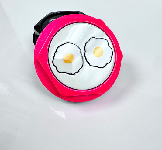 Pink center cap with cartoon-style fried eggs on a white background