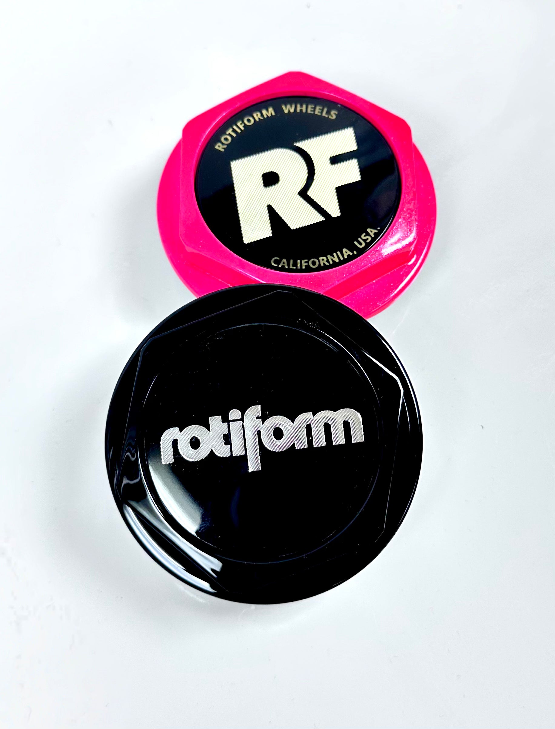 Two car wheel rim caps, one pink and one black, with 'Rotiform' branding on a white background.