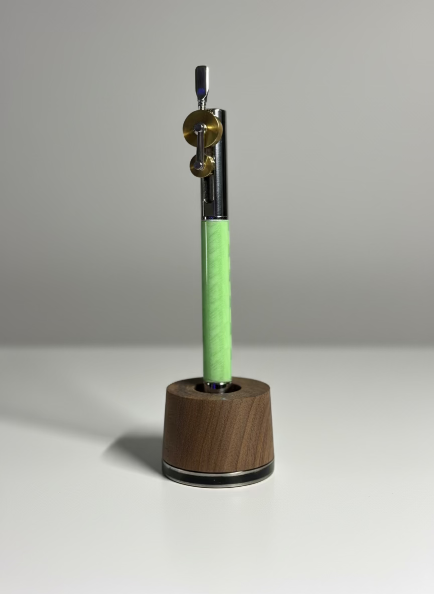 Pen with green clip and wooden base on a gray background