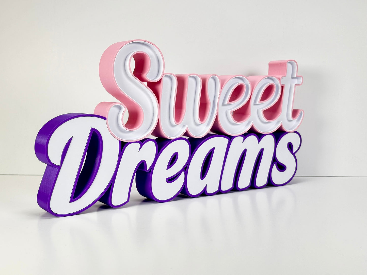 Sweet Dreams LED Channel Sign in vibrant pink and purple colors, featuring the words 'Sweet Dreams' in a stylish font, displayed against a white background. The sign is illuminated, highlighting its elegant and modern design, perfect for home decor