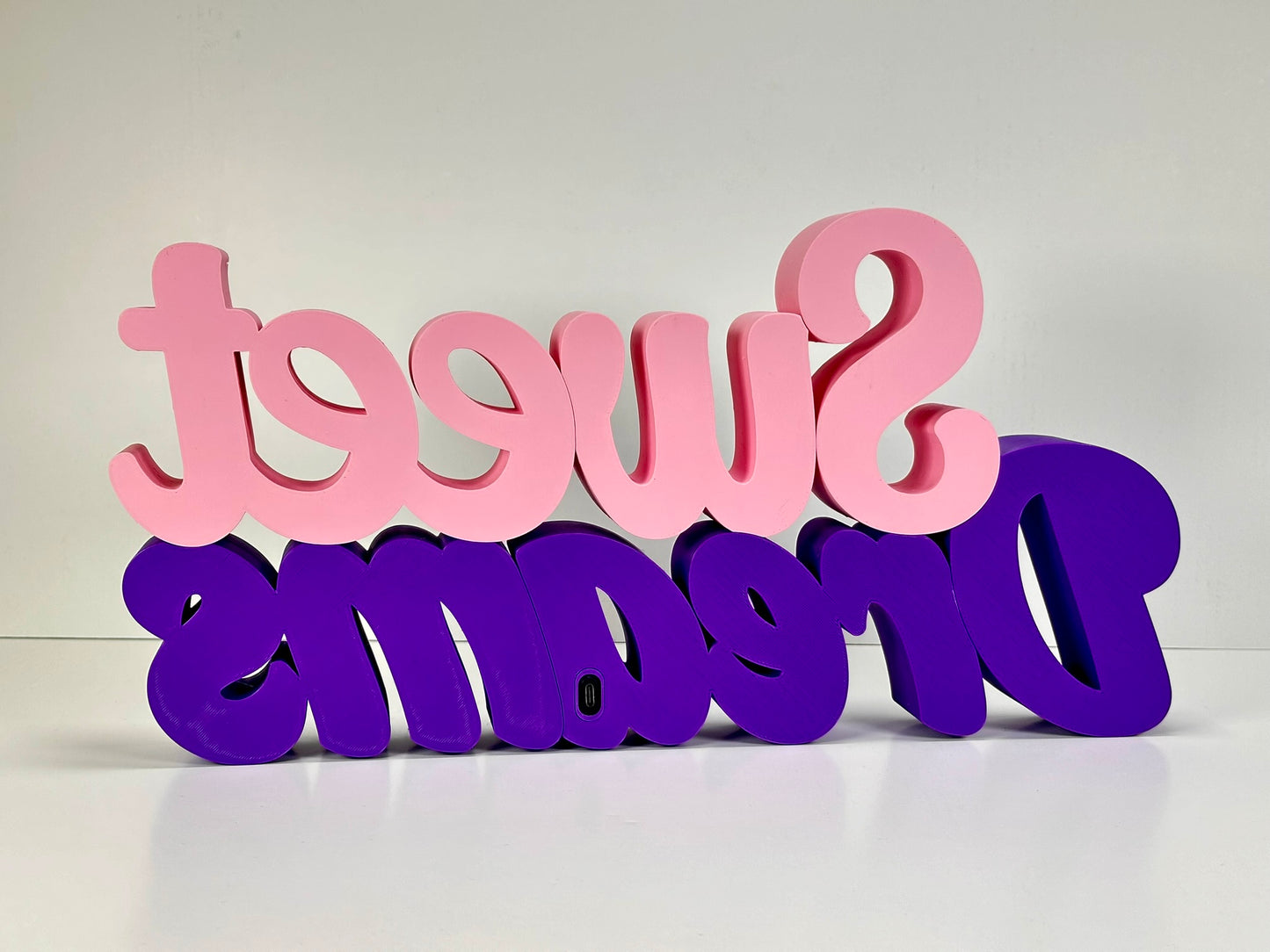 Rear view of the Sweet Dreams LED Channel Sign, showcasing the vibrant pink and purple colors and the back design details. The sign is positioned against a white background, emphasizing its construction and quality, perfect for home decor.