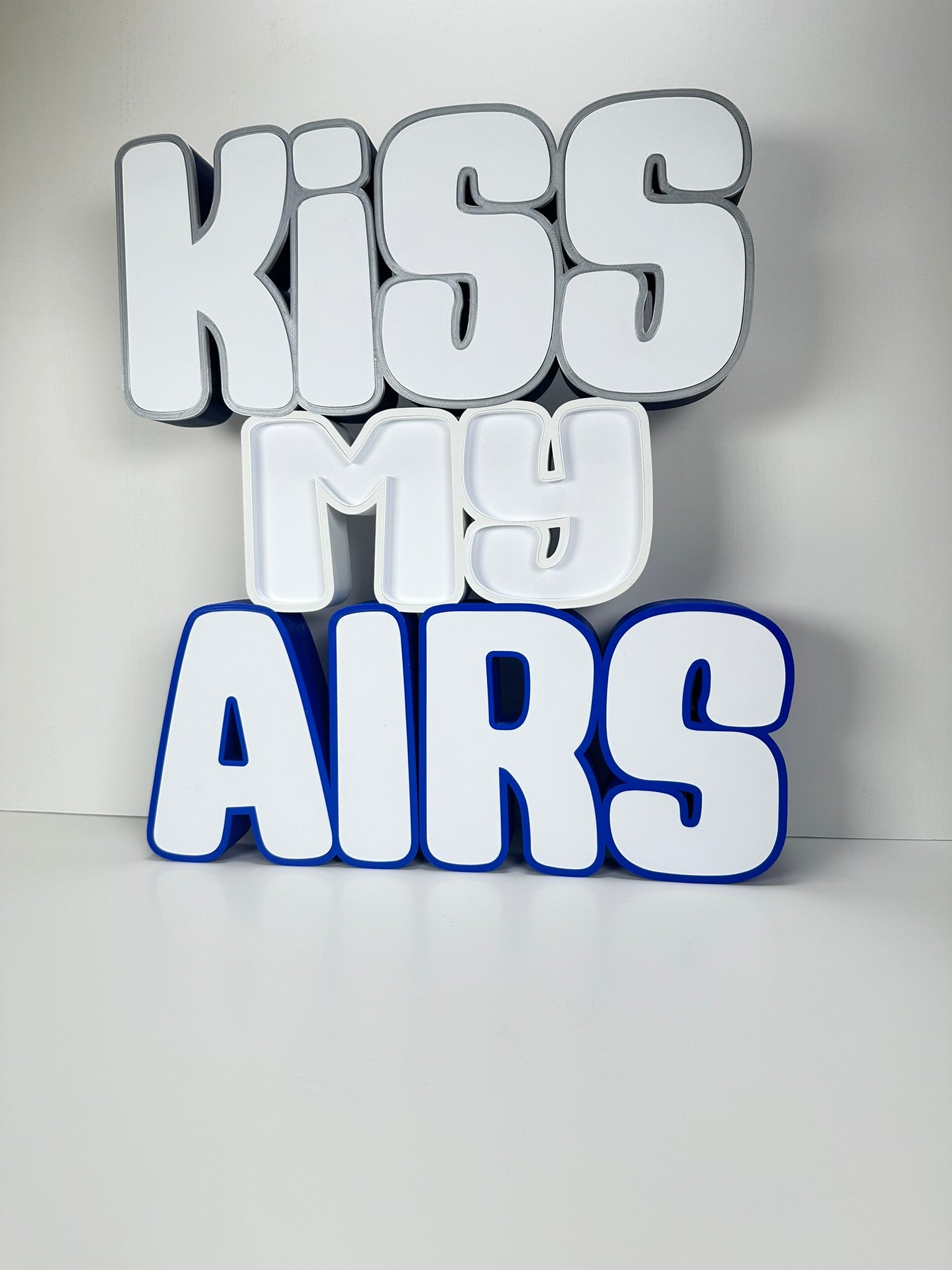 Angled side view of the Kiss My Airs LED Channel Letter Sign, showcasing the 3D structure and bold white letters with black outlines.