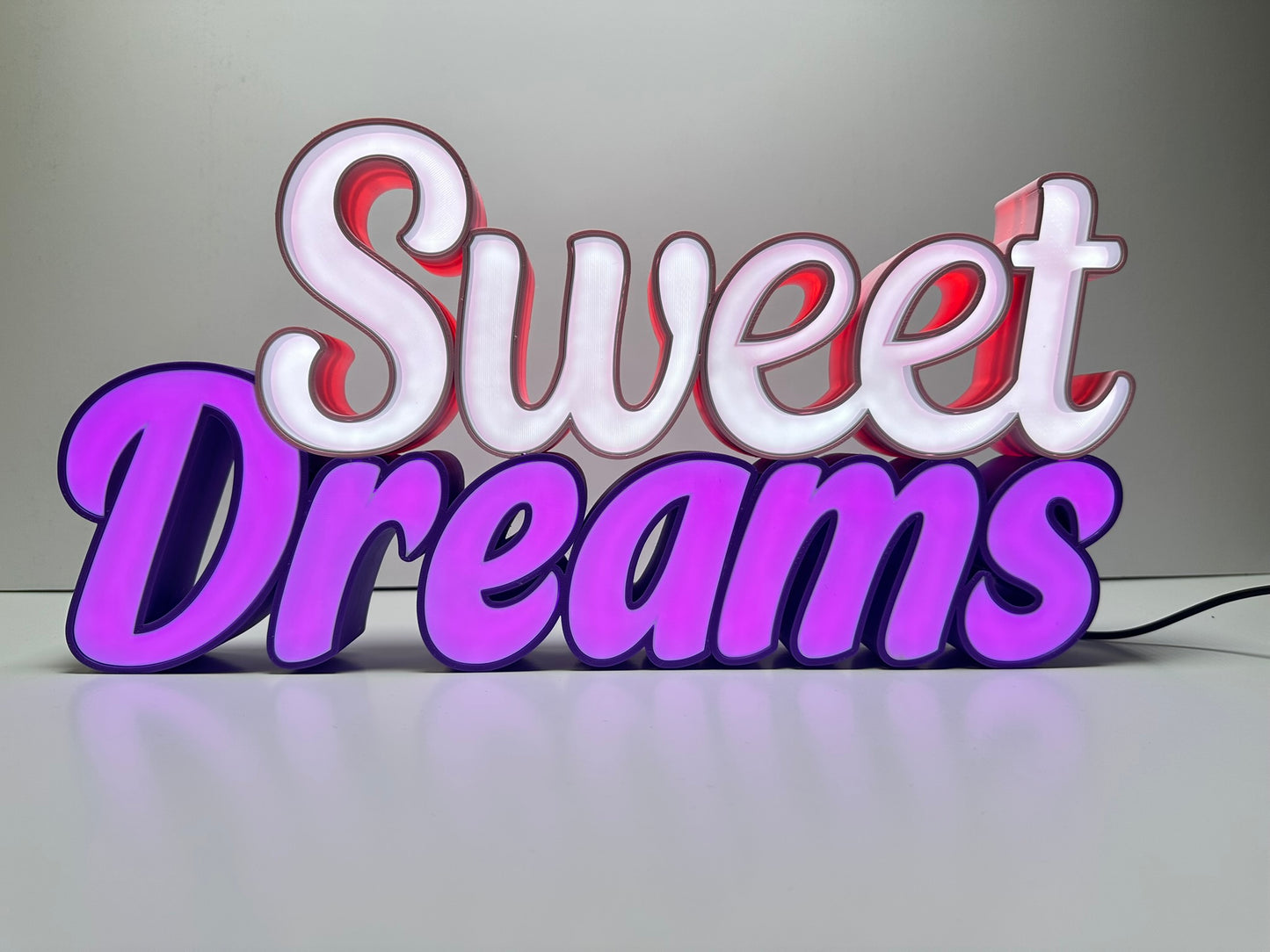 Front view of the Sweet Dreams LED Channel Sign illuminated, displaying vibrant pink and purple LED lights against a white background, ideal for home decor and lighting up spaces