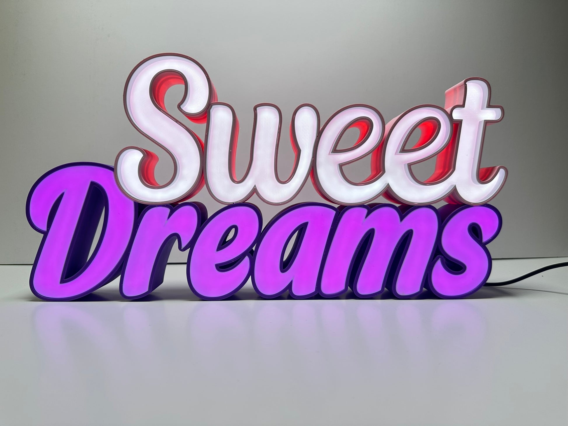 Front view of the Sweet Dreams LED Channel Sign illuminated, displaying vibrant pink and purple LED lights against a white background, ideal for home decor and lighting up spaces