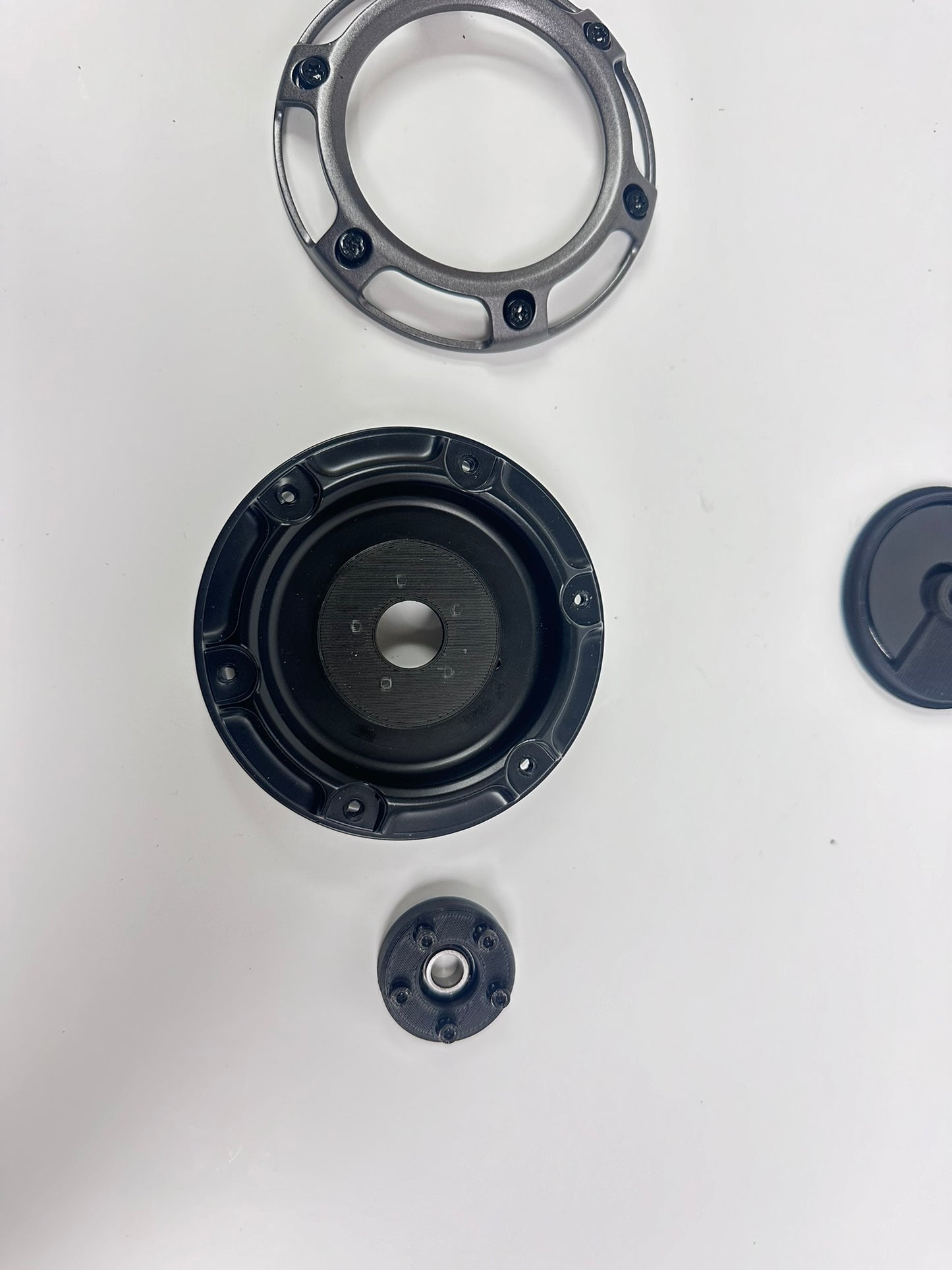 Various components of the Fuel Wheel Floating Center Cap, including the cap, bearing, and stabilizing ring, laid out flat.