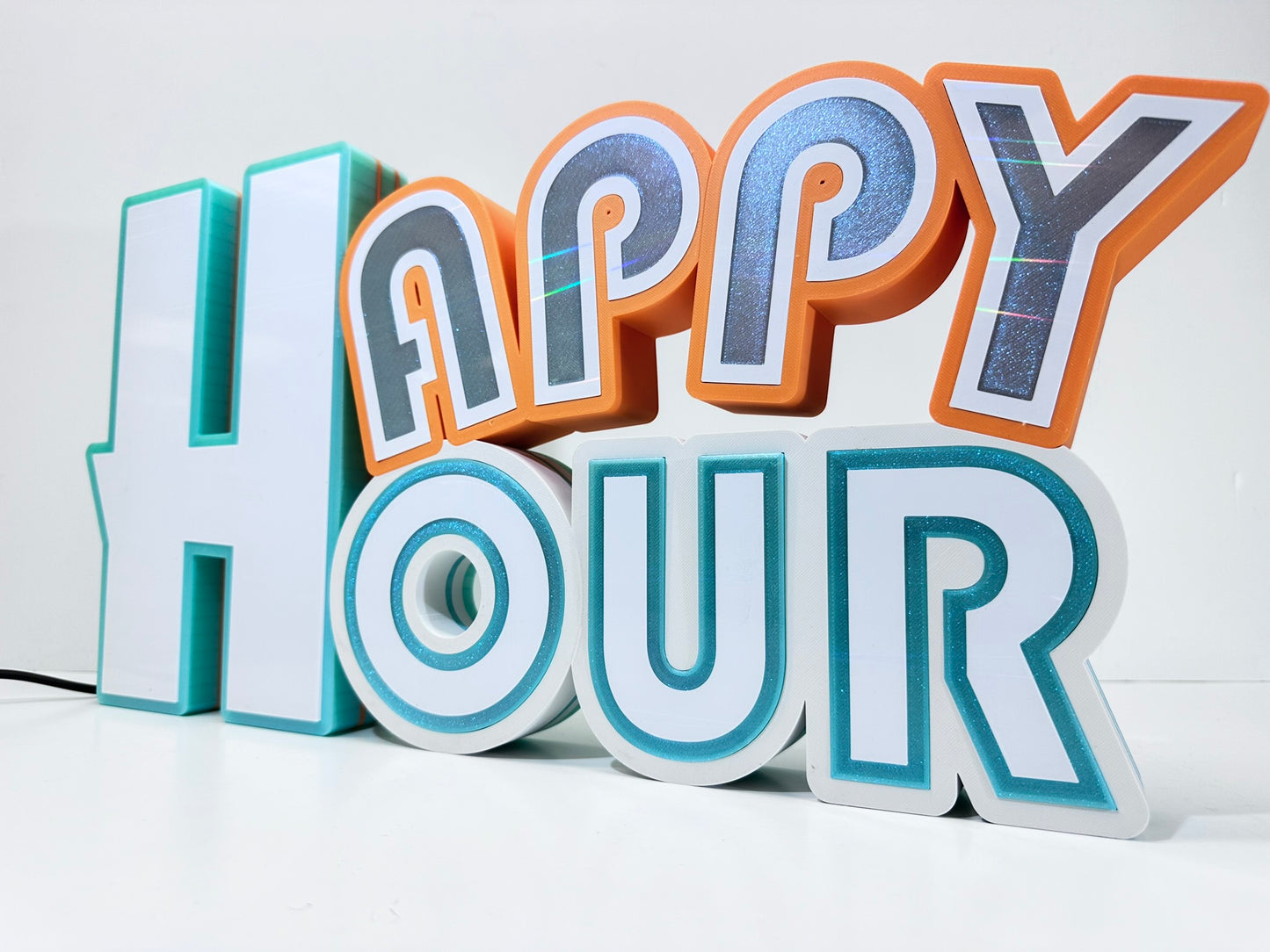 Angled view of the 'Happy Hour' sign in soft ambient light, emphasizing the 3D texture and colorful design.