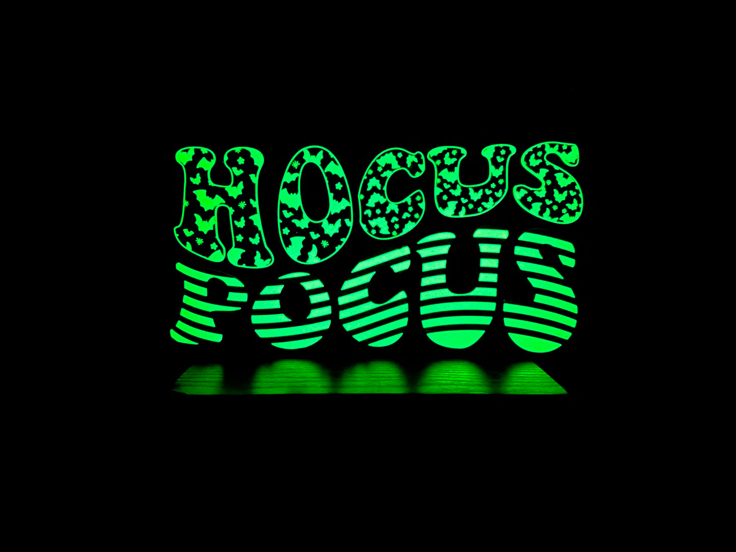 A glowing “Hocus Pocus” LED sign lighting up in the dark, with bold, whimsical text and bat patterns.