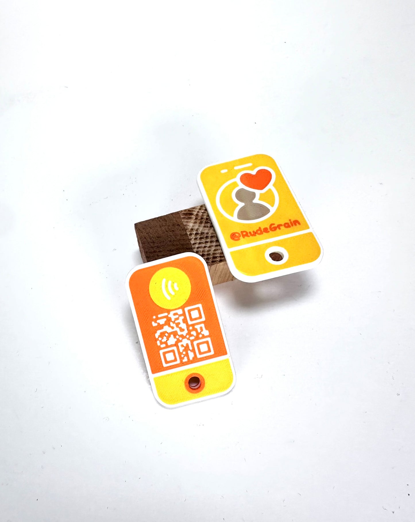 Two NFC/QR tags in yellow and orange displayed together, highlighting the QR code and branding design.