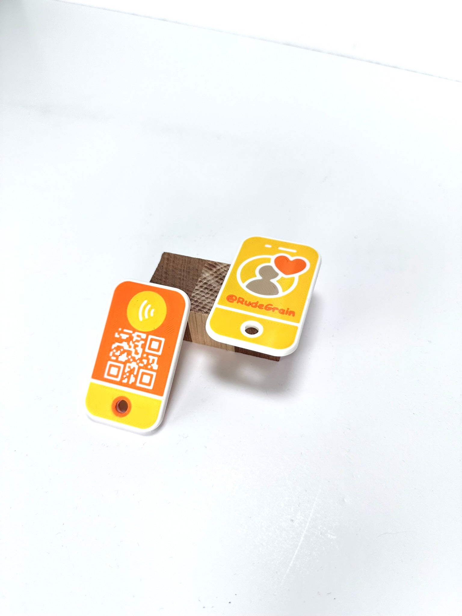 NFC/QR tags in vibrant yellow and orange, positioned upright on a clean white surface.