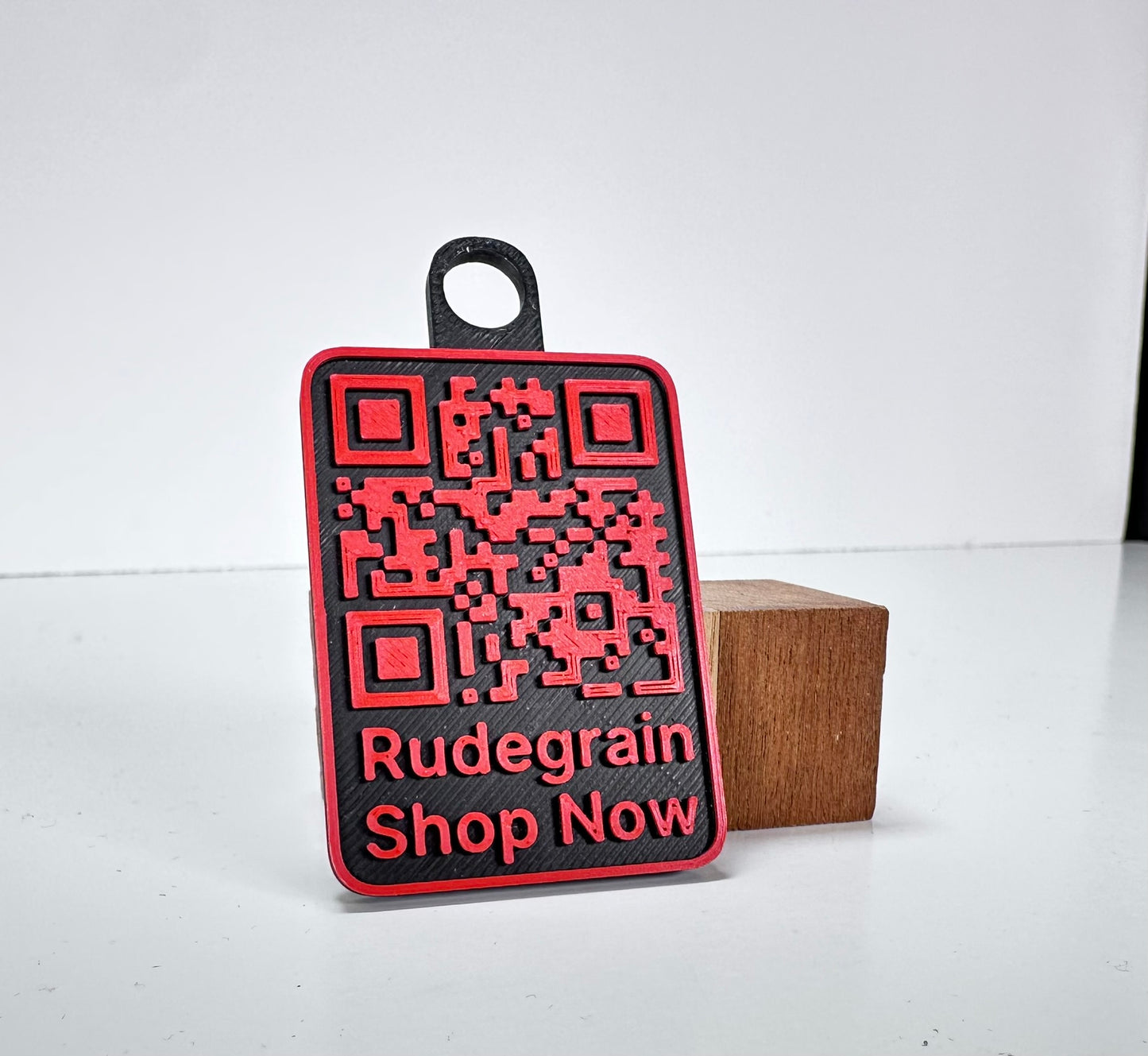 Red and black NFC/QR tag with the text 'RudeGrain Shop Now' and a detailed QR code design.